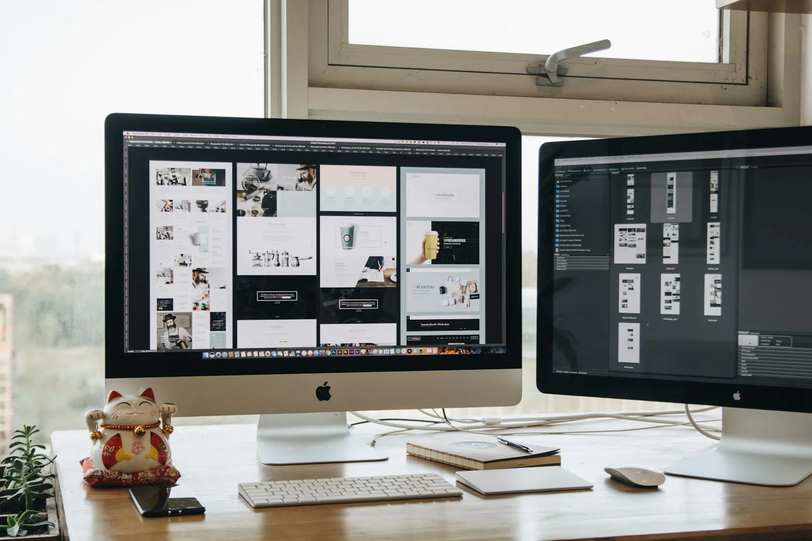Web designer’s desk with two monitors showing website layouts